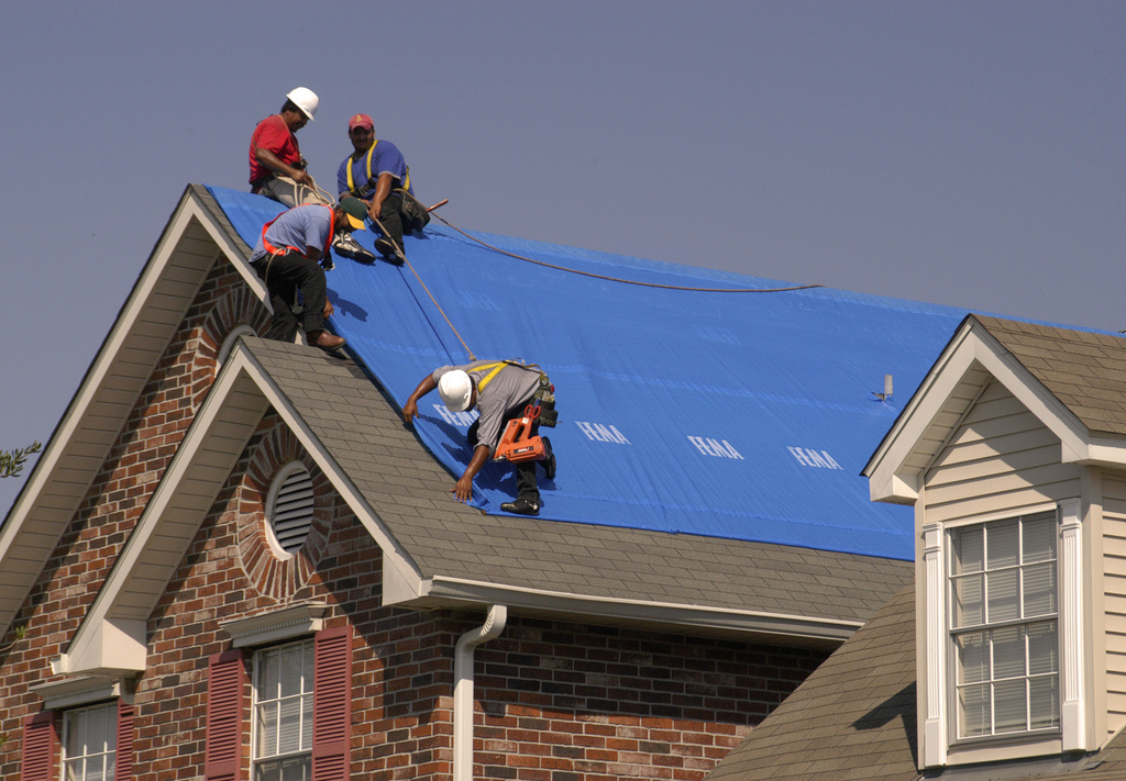 installing a tarp on the roof of a house
